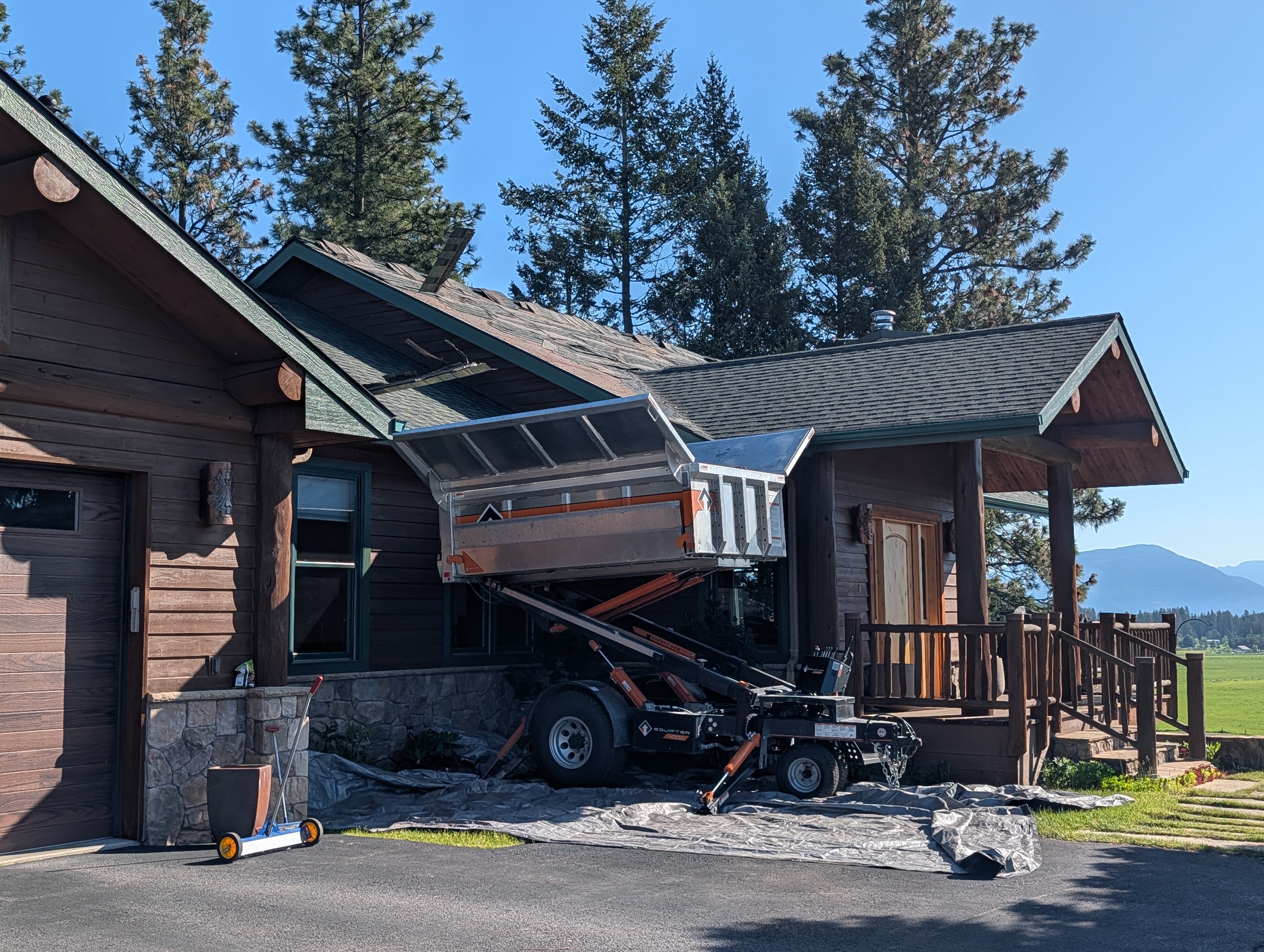 Shingle roof replacement in progress with an Equipter lift on site in Whitefish, Montana by Grizzly Ridge Roofing & Exteriors