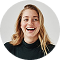 Smiling woman with blonde hair wearing a black top against a white background.