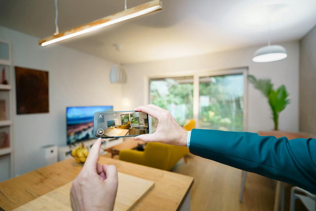 Person pointing a smartphone at a living room floor to visualize furniture placement on a detected surface