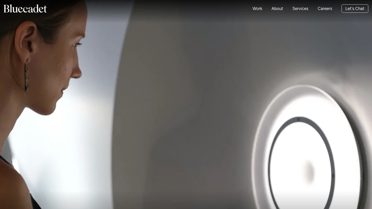 Bluecadet website homepage, showing a visitor looking into a large illuminated ring-shaped museum installation.