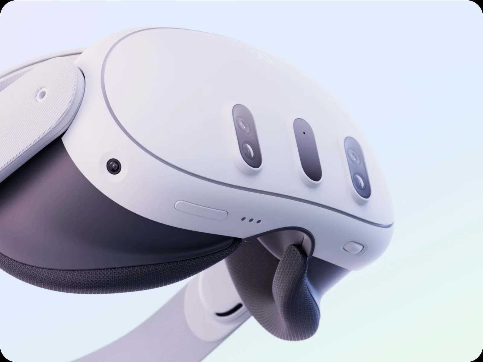 Close-up of a white Meta Quest 3 headset at an angle, showing the three vertical camera slots across the front and the fabric head strap