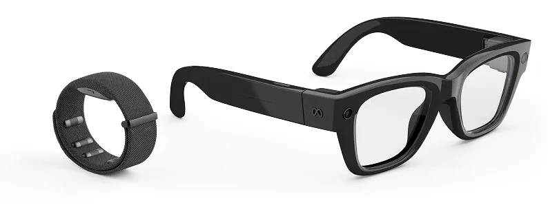 Meta Ray-Ban Display glasses beside the Meta Neural Band on white, the glasses folded at three quarters and the black fabric band standing upright next to them