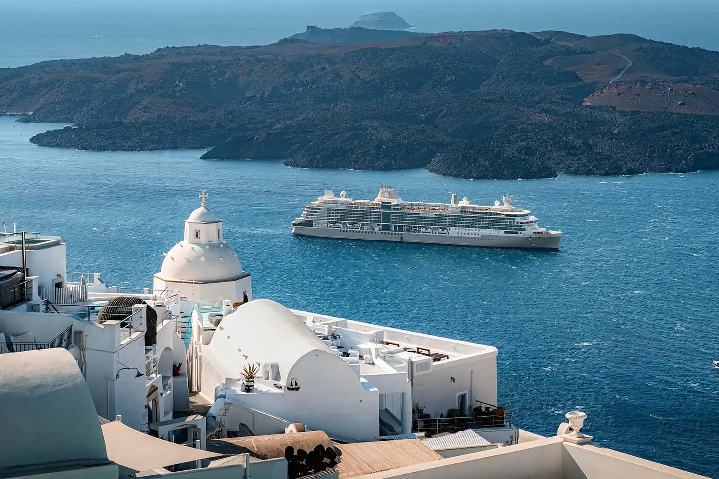 Cruise ship sailing past the whitewashed cliffs of Santorini, Greece