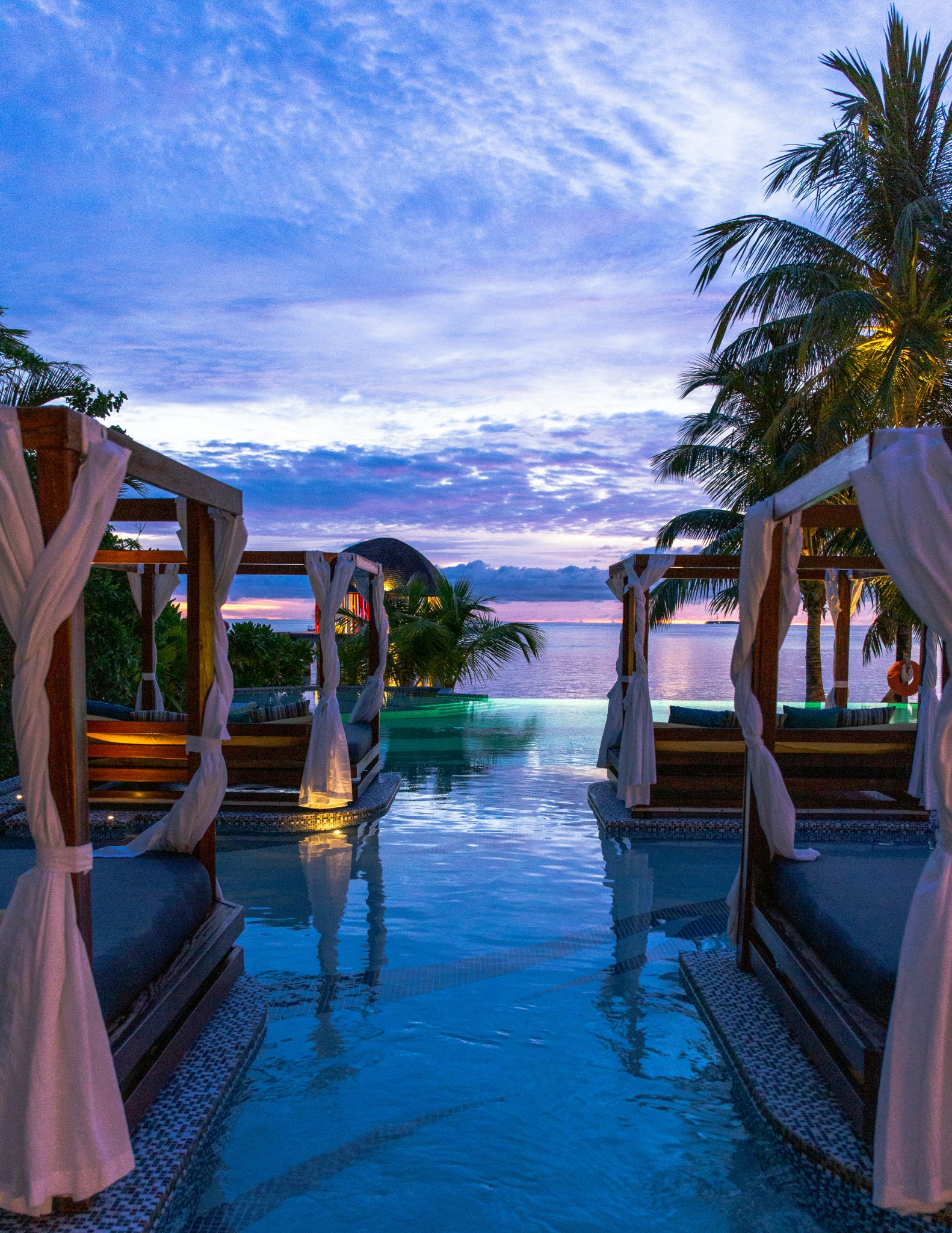 Luxury waterfront resort with private cabanas and an infinity pool at sunset