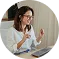 Smiling woman with glasses holding a credit card and phone, wearing headphones and casual clothes.