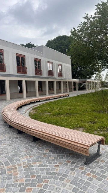 Gebogen houten zitbank langs het groene plein aan het gemeentehuis