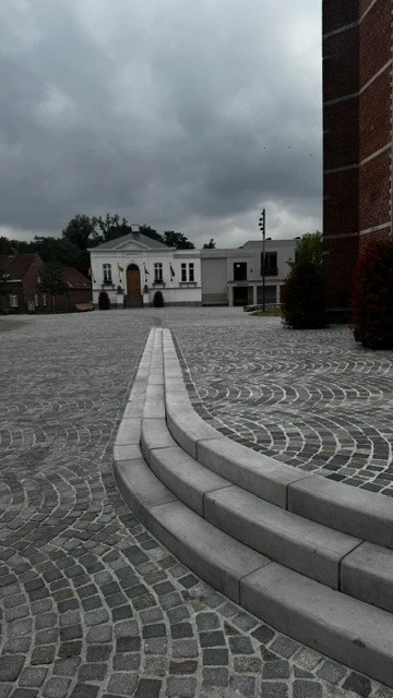 Brede traptreden in het kasseiplein aan de kerk