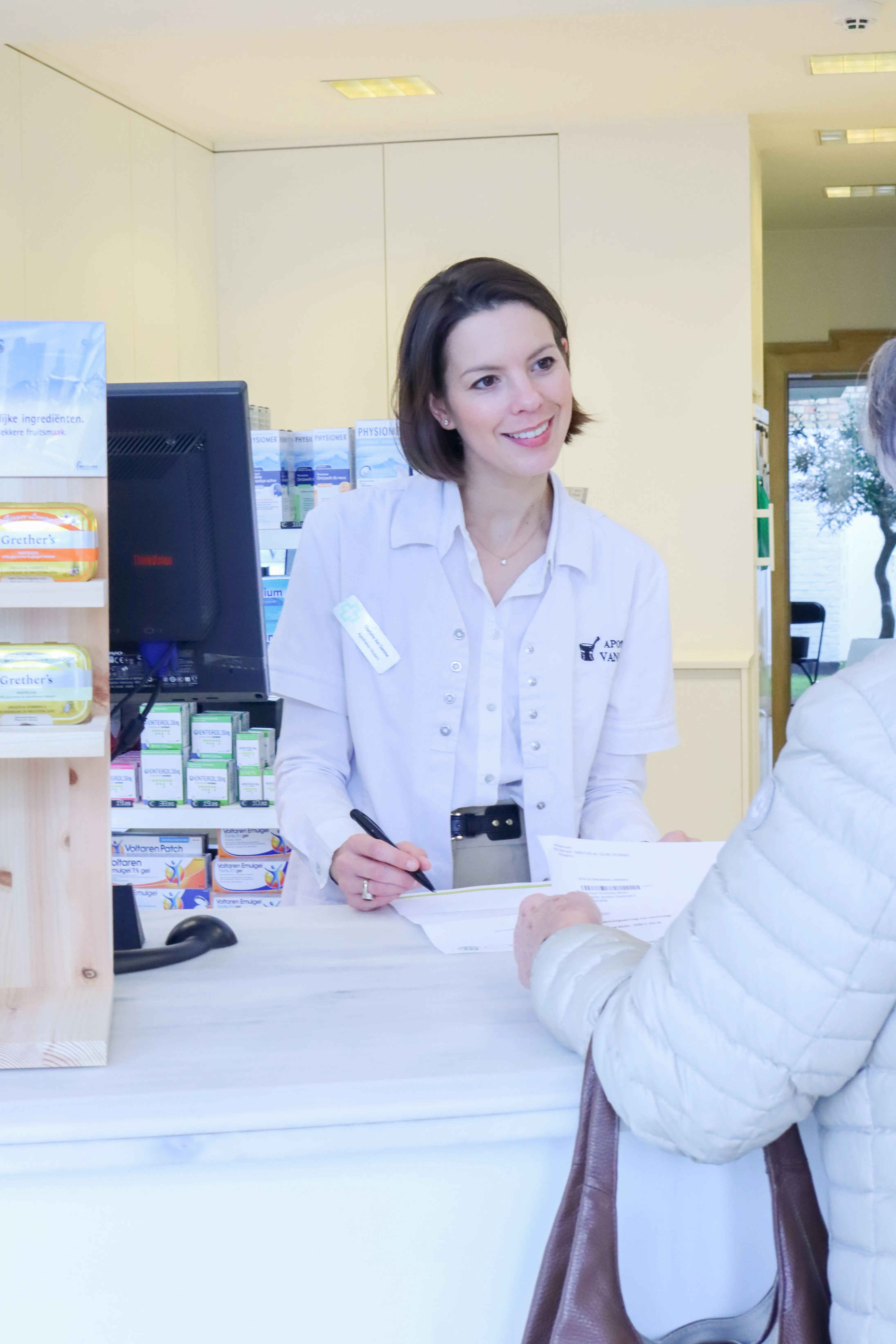 Apotheker helpt klant persoonlijk aan de balie bij Apotheek Van Damme