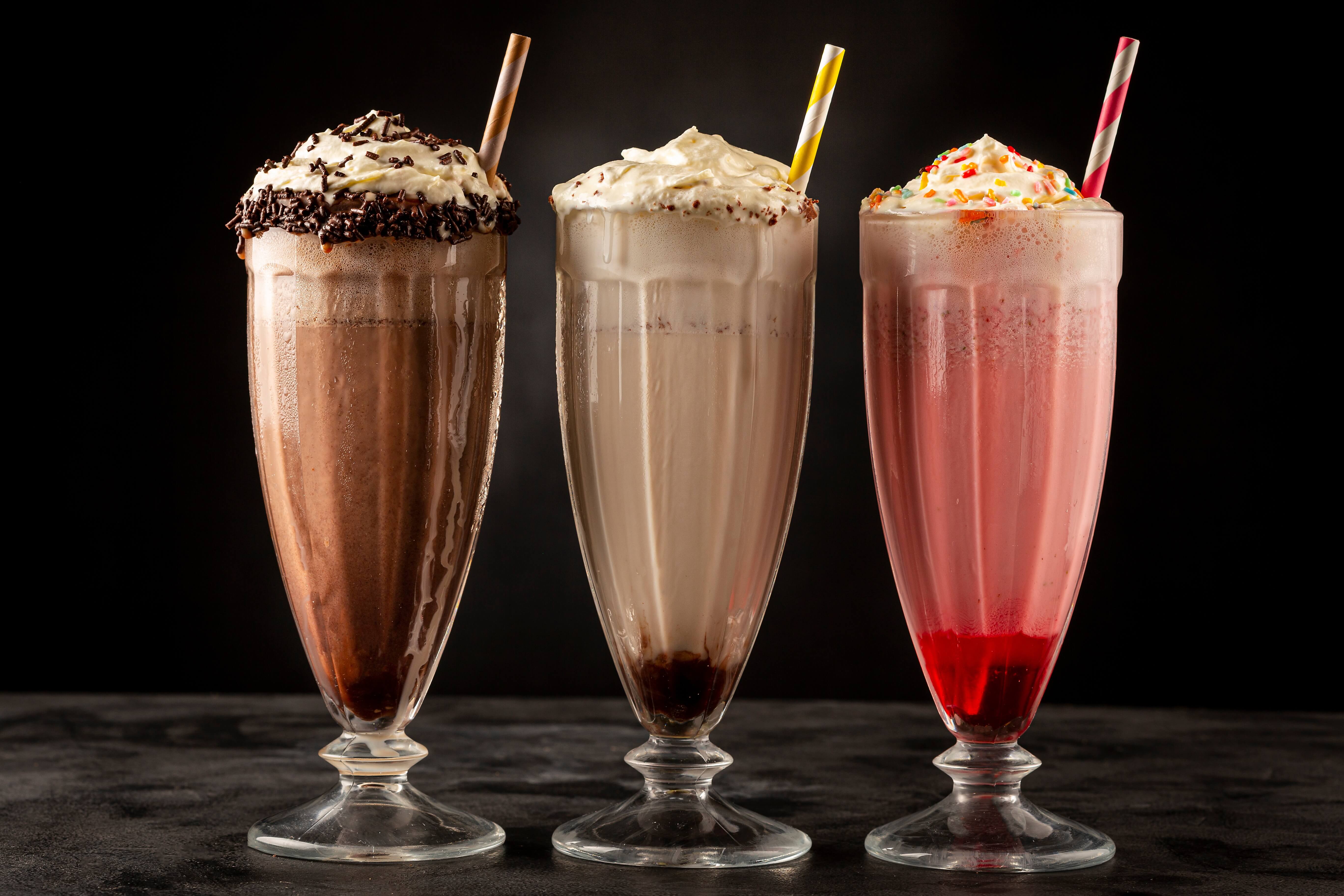 Three milkshakes—chocolate, vanilla, and strawberry—topped with whipped cream