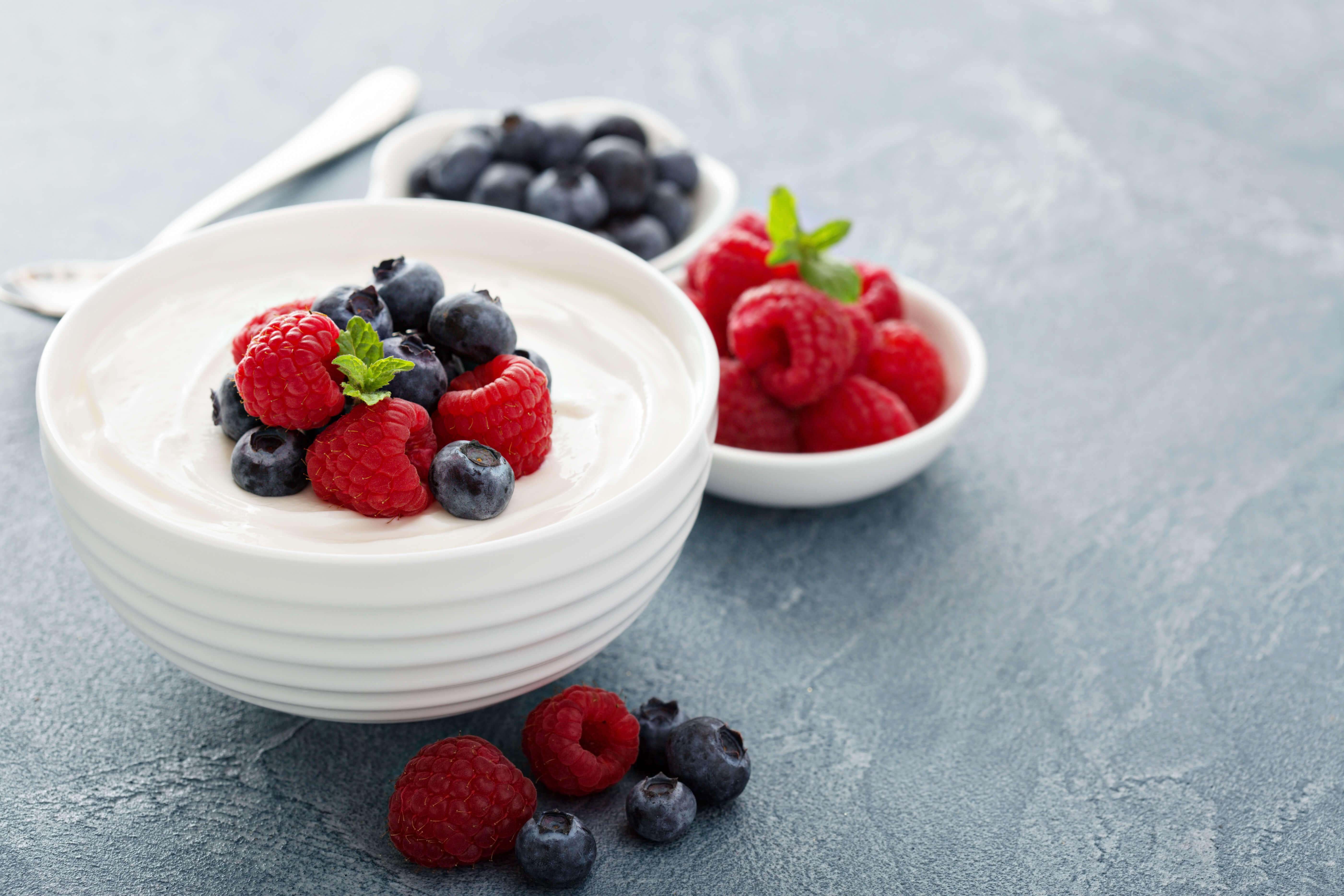 Bowl of yogurt topped with fresh raspberries and blueberries