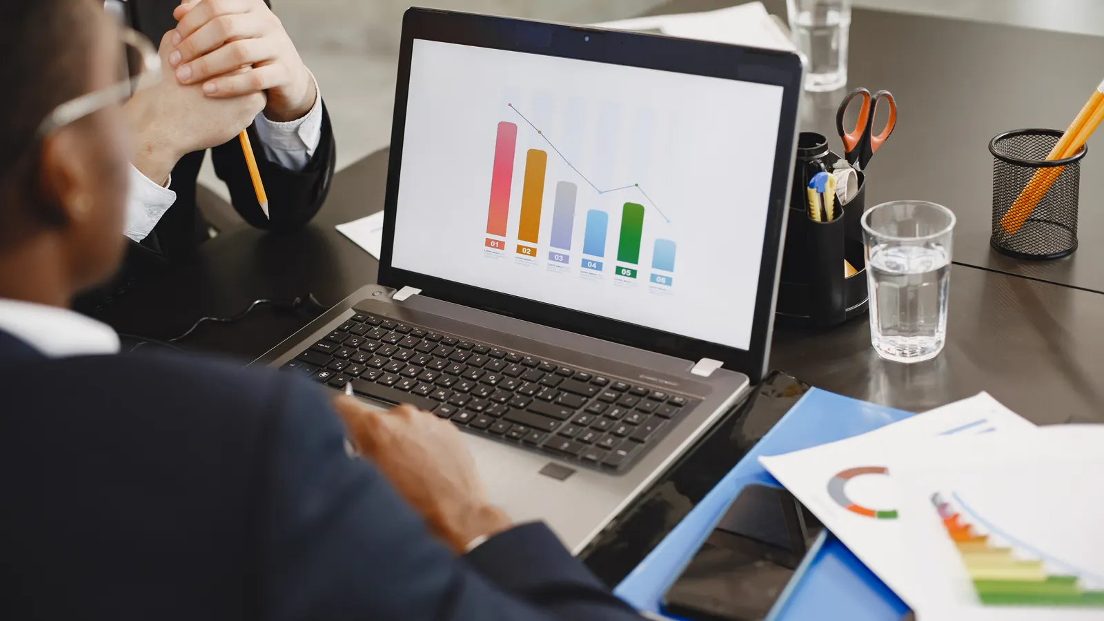 Business professionals reviewing performance graphs on a laptop while comparing paid search and SEO investment