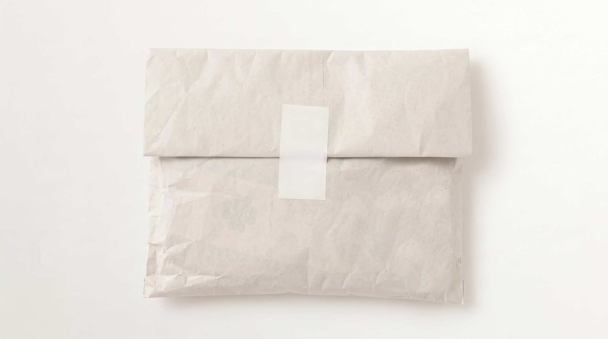 Cream paper garment pouch folded closed with a blank white label seal