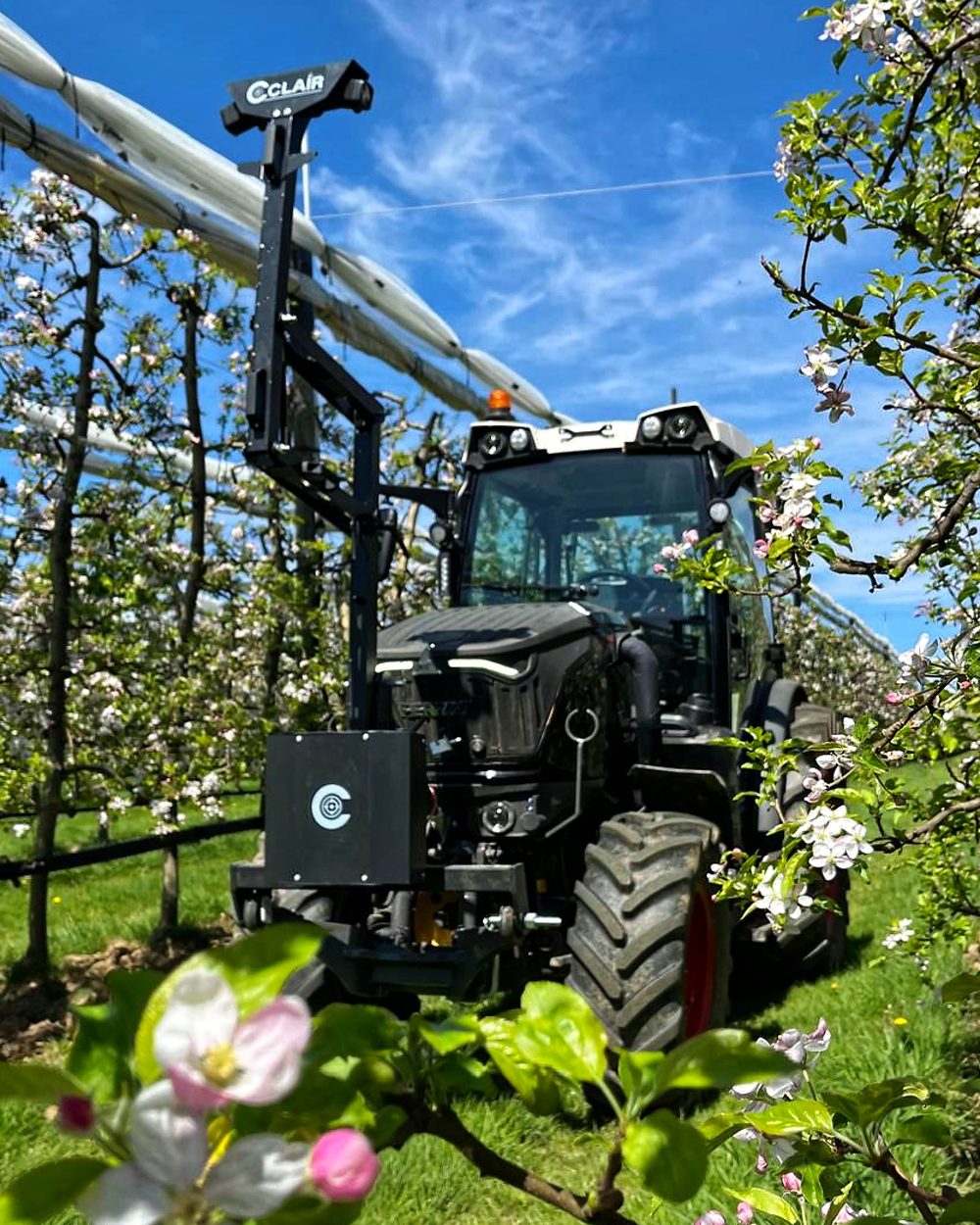 The Cclair acquisition unit mounted on the front of a tractor, mapping an apple orchard at full bloom