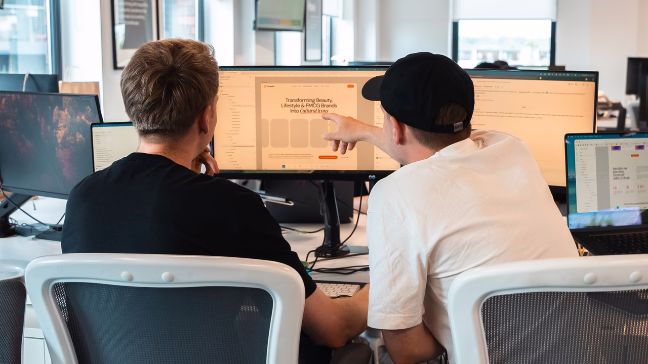 Two Campfire team members reviewing a design on a large monitor