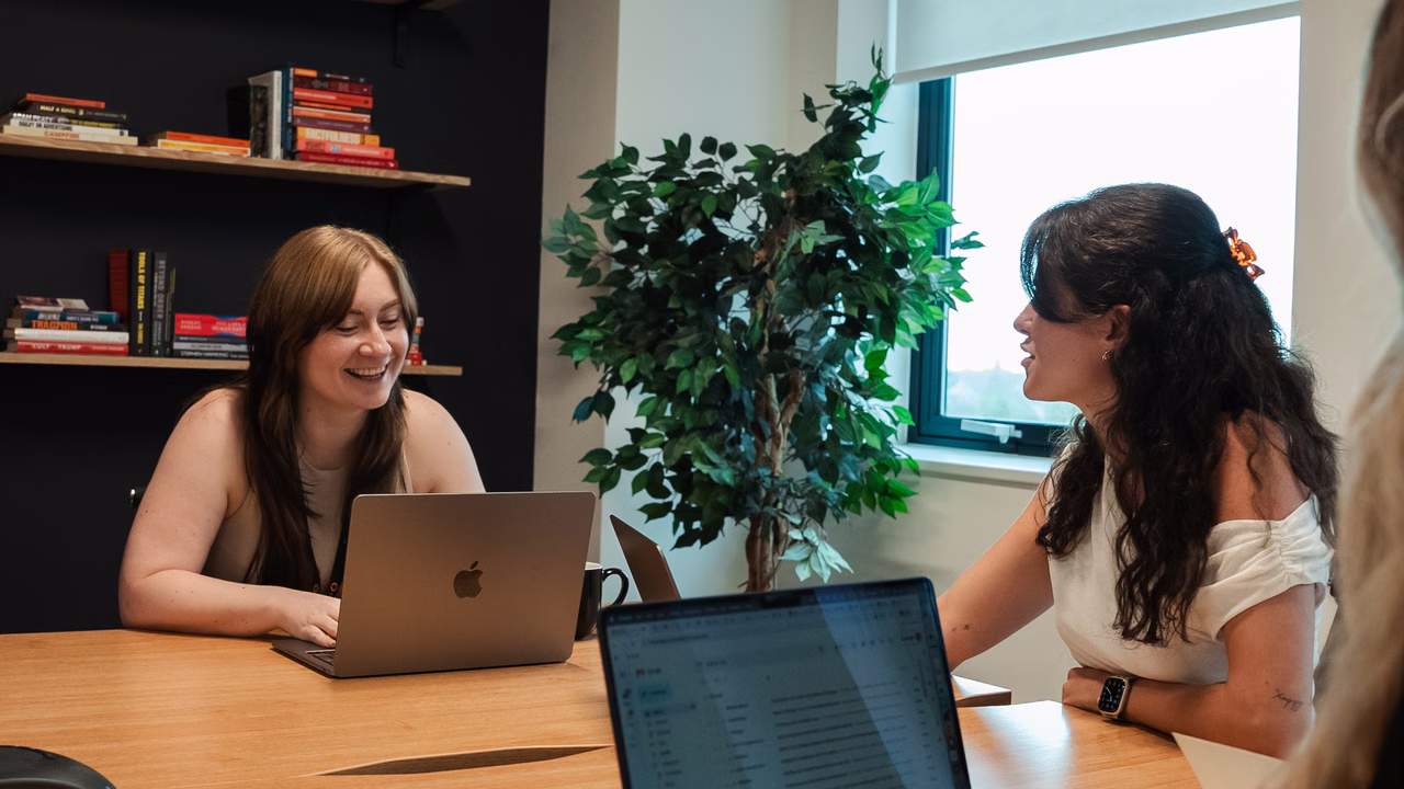 Two Campfire team members talking over laptops in a meeting room