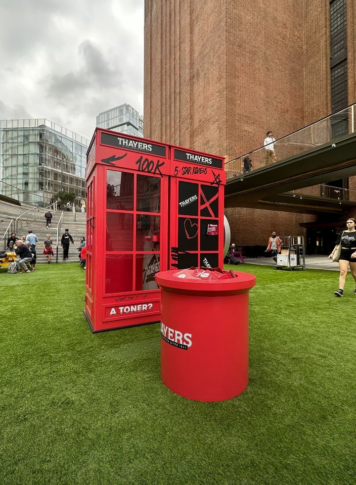 Red Thayers "What the F*** is a toner?" phone box pop-up with a branded sampling stand on the lawn