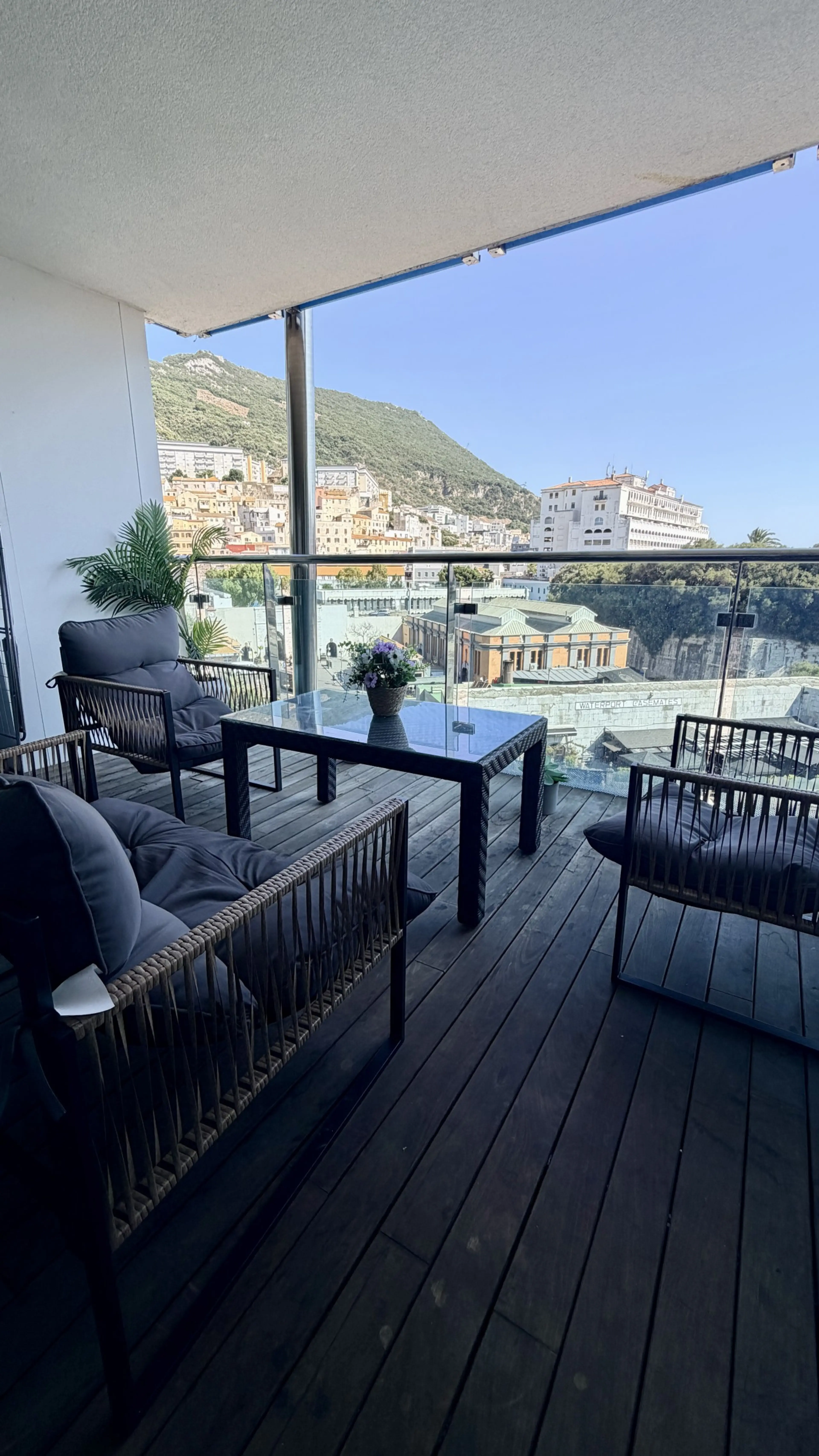 Furnished apartment balcony in Gibraltar with seating, a table and a view of the Rock and the town