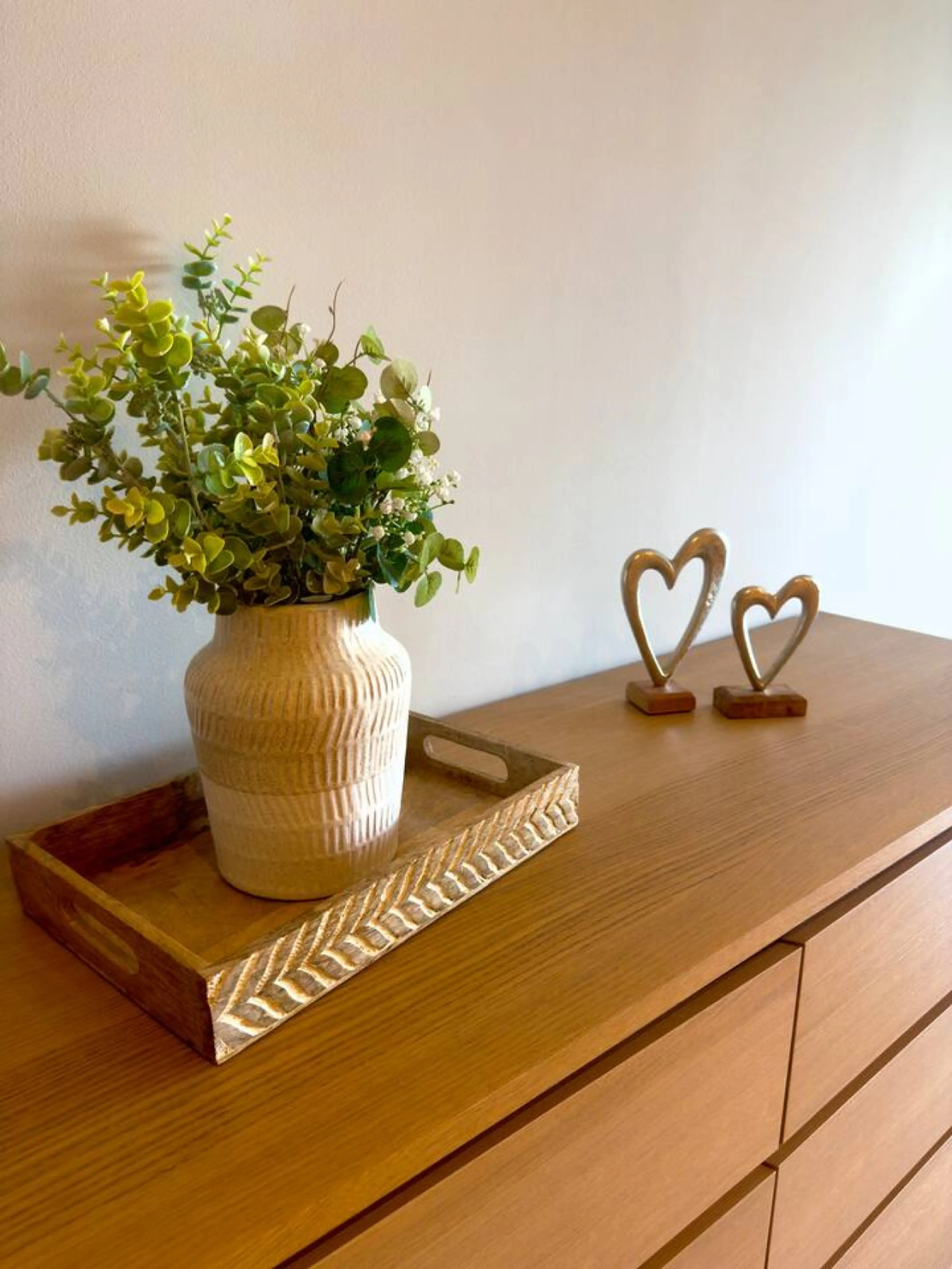 Sideboard in a Vista Ventures apartment with a plant in a ceramic vase on a wooden tray