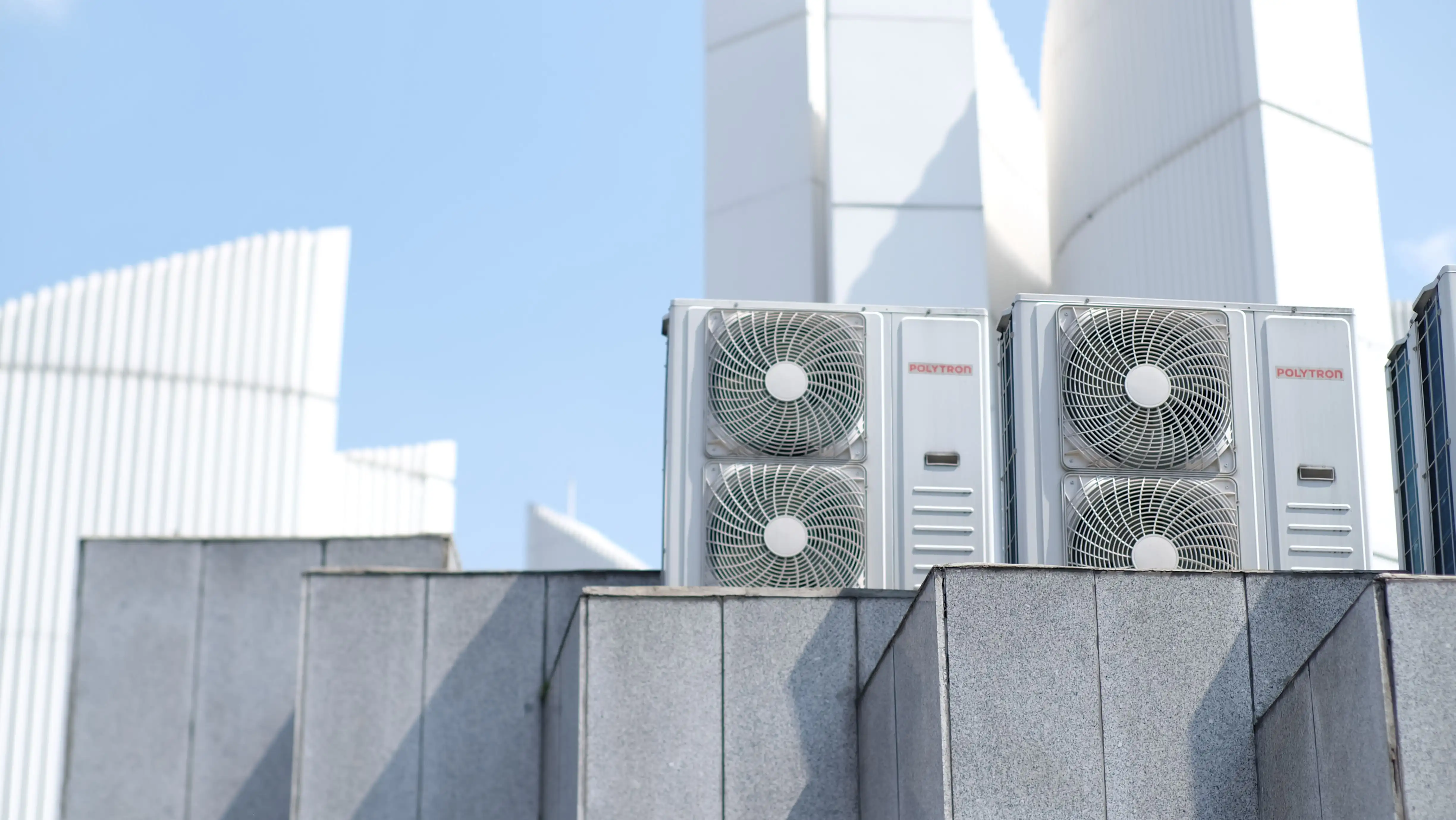 An outdoor air conditioning unit near some flowers.