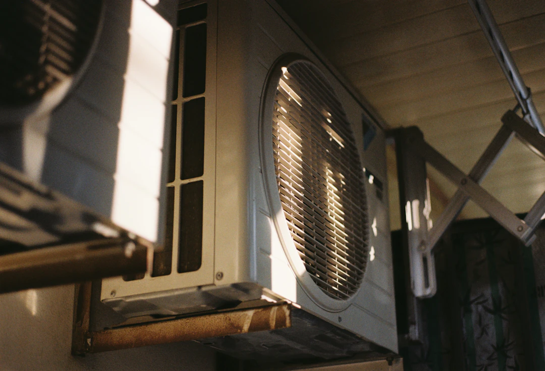 An outdoor air conditioning unit near some flowers.