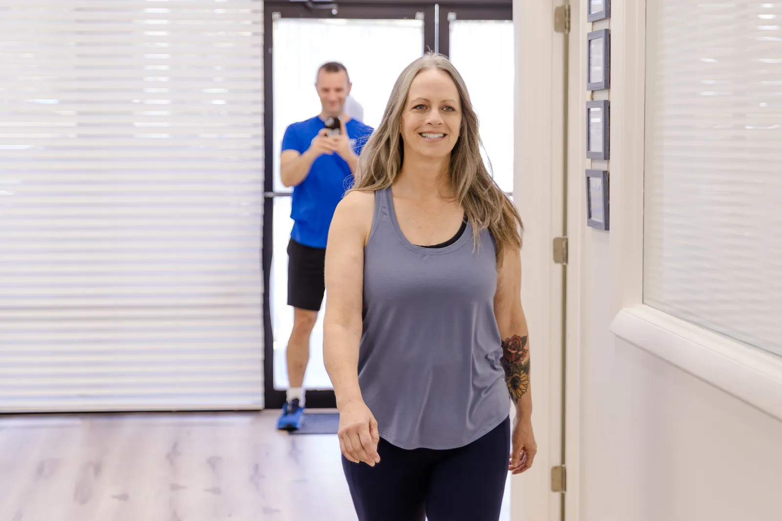 Renew patient walking down the hallway while Dr. Matt Rieder, DPT, films her posture and walk on his phone in St. Augustine