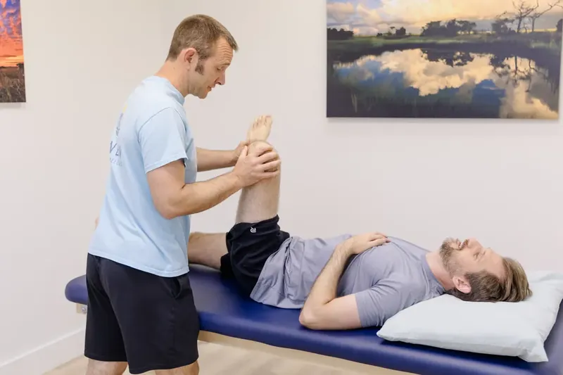 Matt Rieder, DPT, lifting a patient's straight leg on the table to check the sciatic nerve at Renew Strength & Wellness in St. Augustine, FL