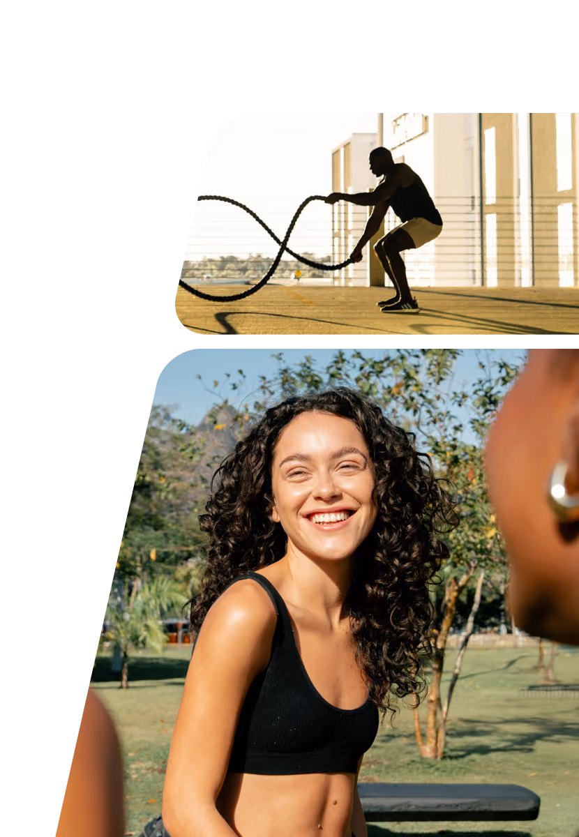 A man in athletic clothing is exercising outdoors with battle ropes against an industrial building, while below, a smiling woman with curly hair in a black sports bra is outdoors on grass, engaging with a group in a friendly conversation.