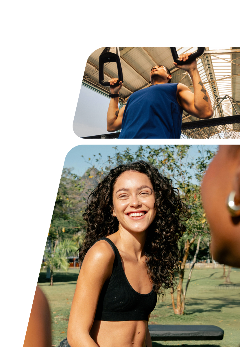 A man in athletic clothing is exercising outdoors with battle ropes against an industrial building, while below, a smiling woman with curly hair in a black sports bra is outdoors on grass, engaging with a group in a friendly conversation.