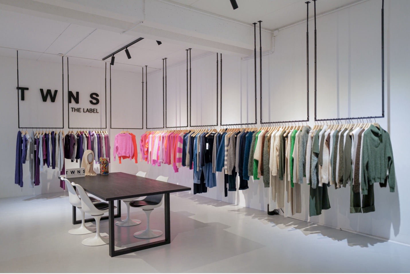 Inside the TWNS showroom at Trademart Brussels, with racks of colourful knitwear beneath the brand's wall signage