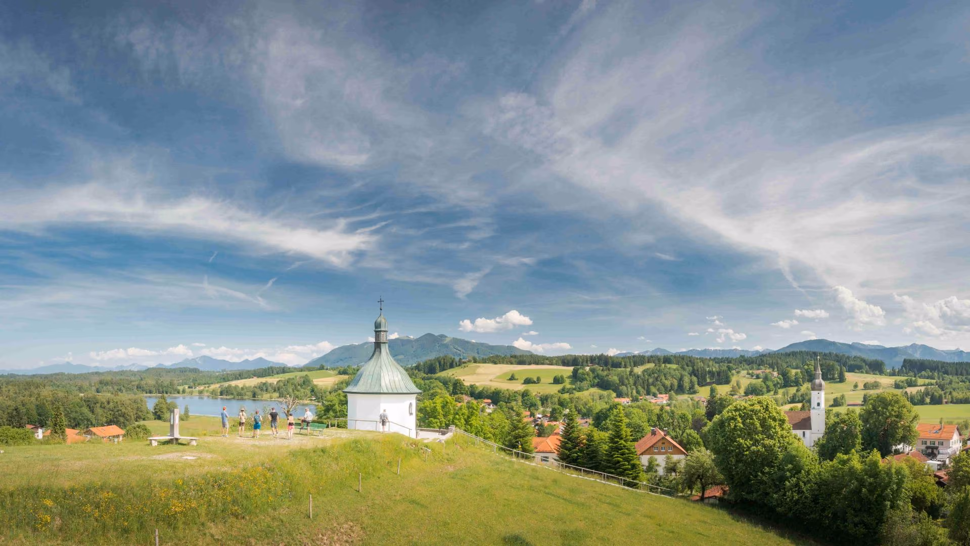 Landschaft bei Bad Bayersoien mit kleiner Kapelle auf einem Hügel, See, Dorf und Alpenpanorama