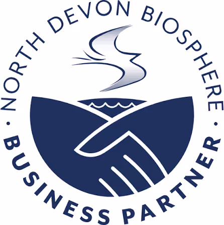 Logo showing two hands shaking in front of a stylized landscape with hills and water, surrounded by the text 'North Devon Biosphere Business Partner'.