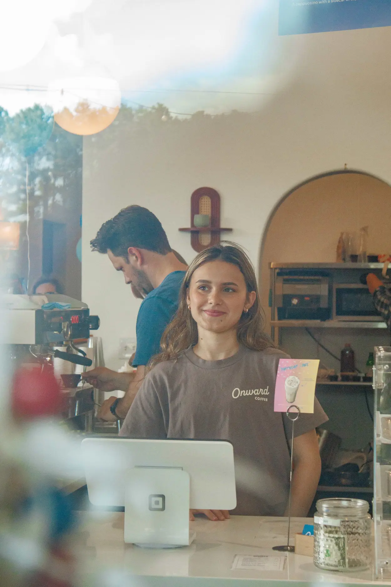 Barista pouring latte art into an iced drink at Onward Coffee