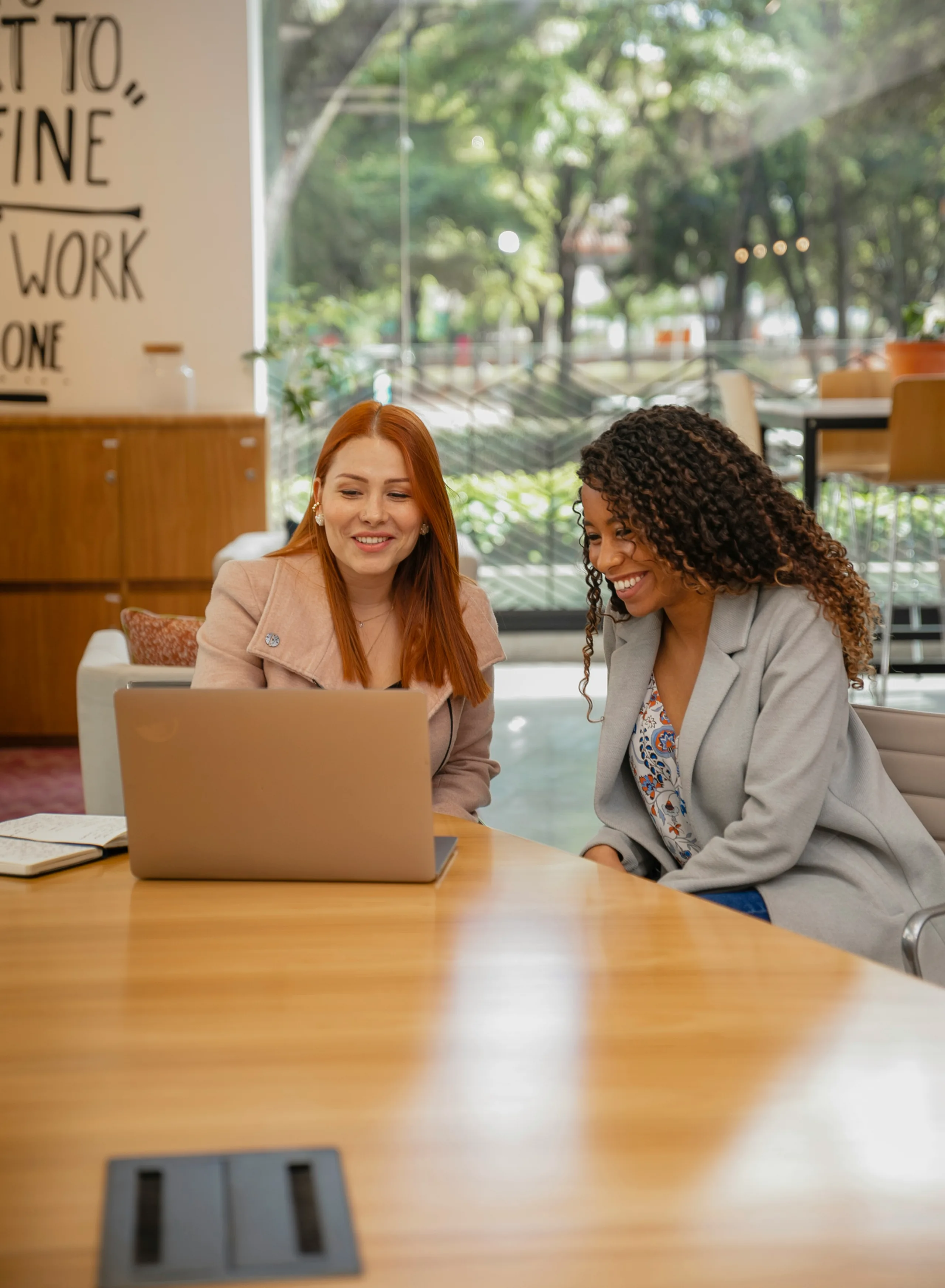 Two colleagues smiling at a laptop in a bright office