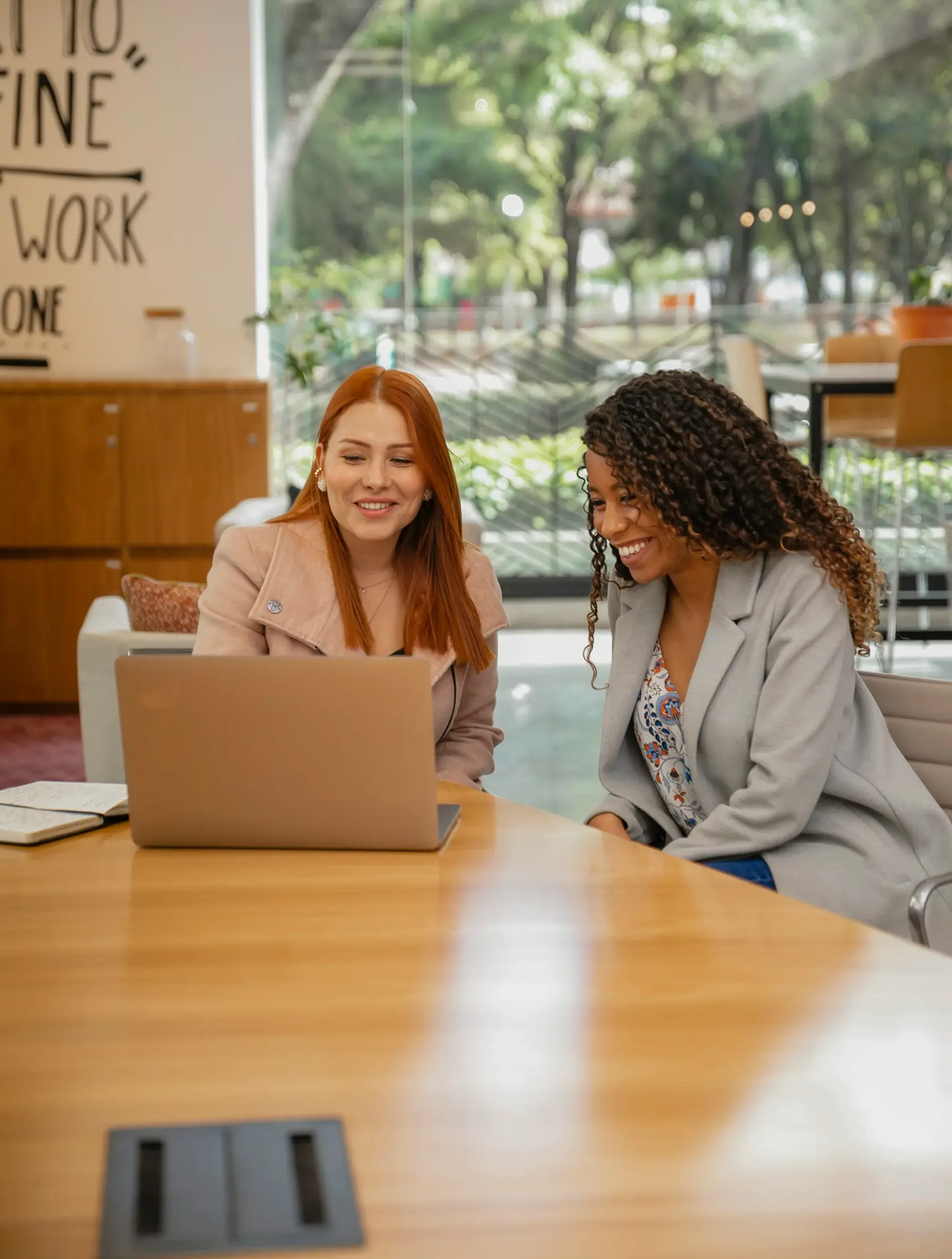 Two colleagues smiling at a laptop in a bright office