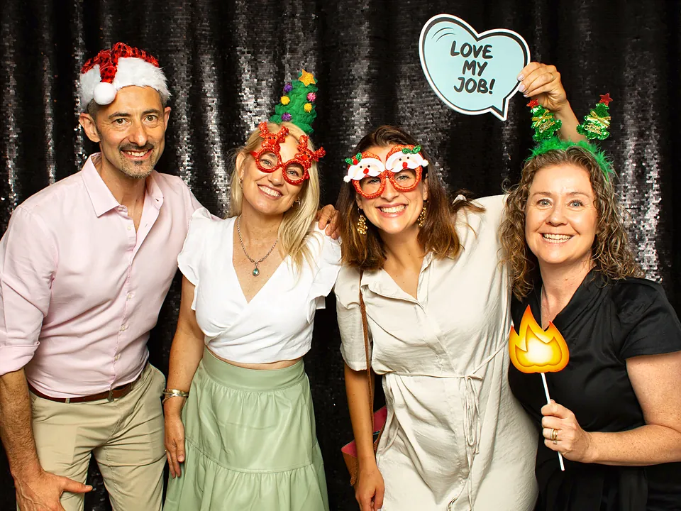 Four StrataMax team members in Christmas hats at a party photo booth
