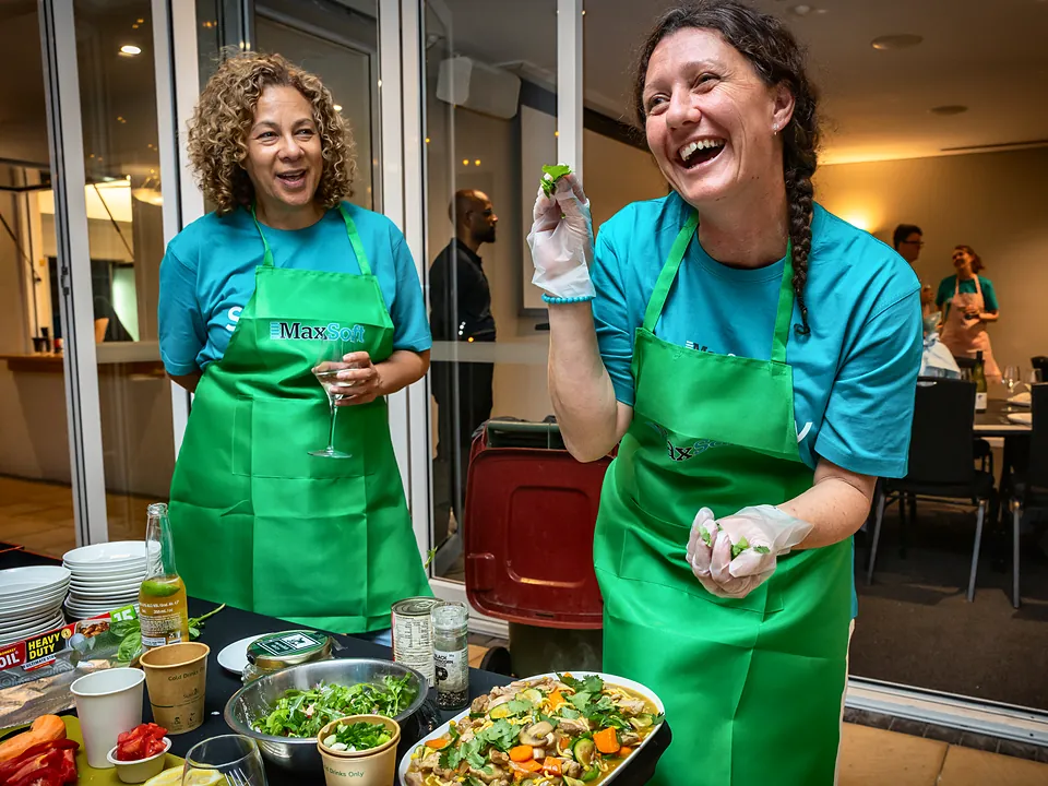Two StrataMax team members laughing during a team cooking challenge