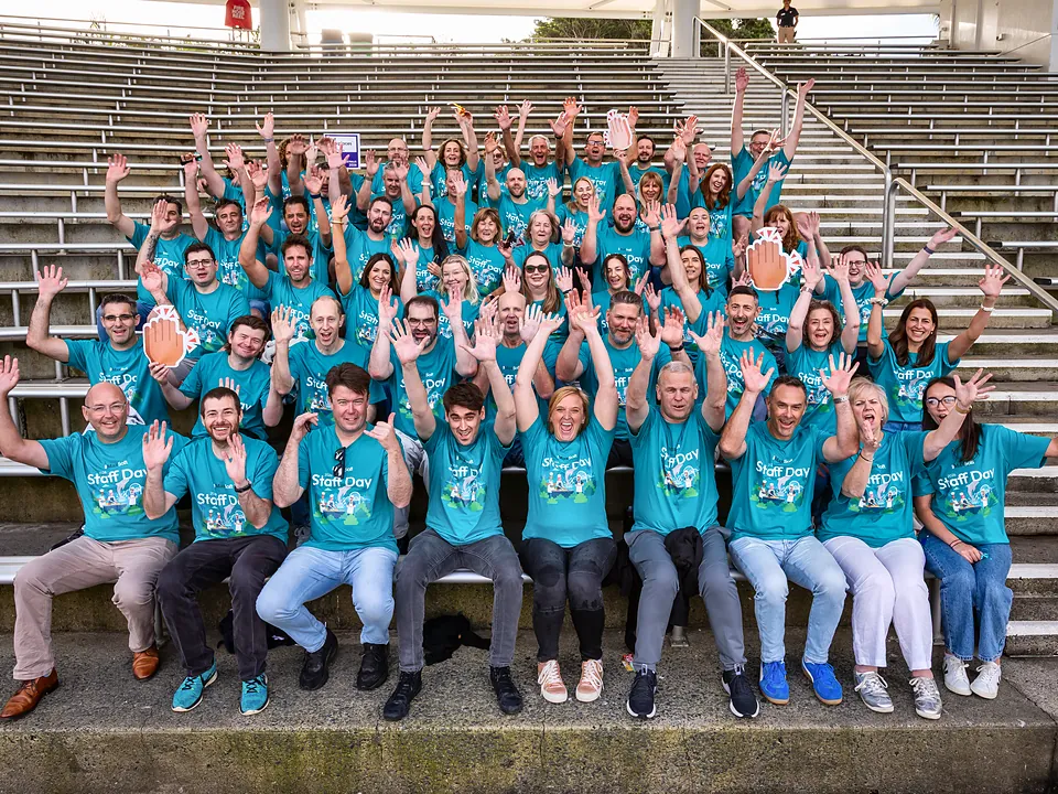 StrataMax team in Staff Day shirts waving from a grandstand