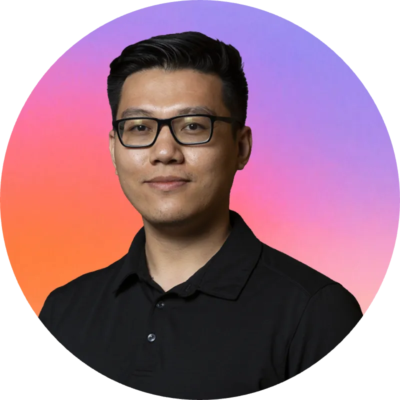 Portrait of a man with short black hair and glasses wearing a black collared shirt, smiling slightly against a circular gradient of pink, orange, and purple hues.