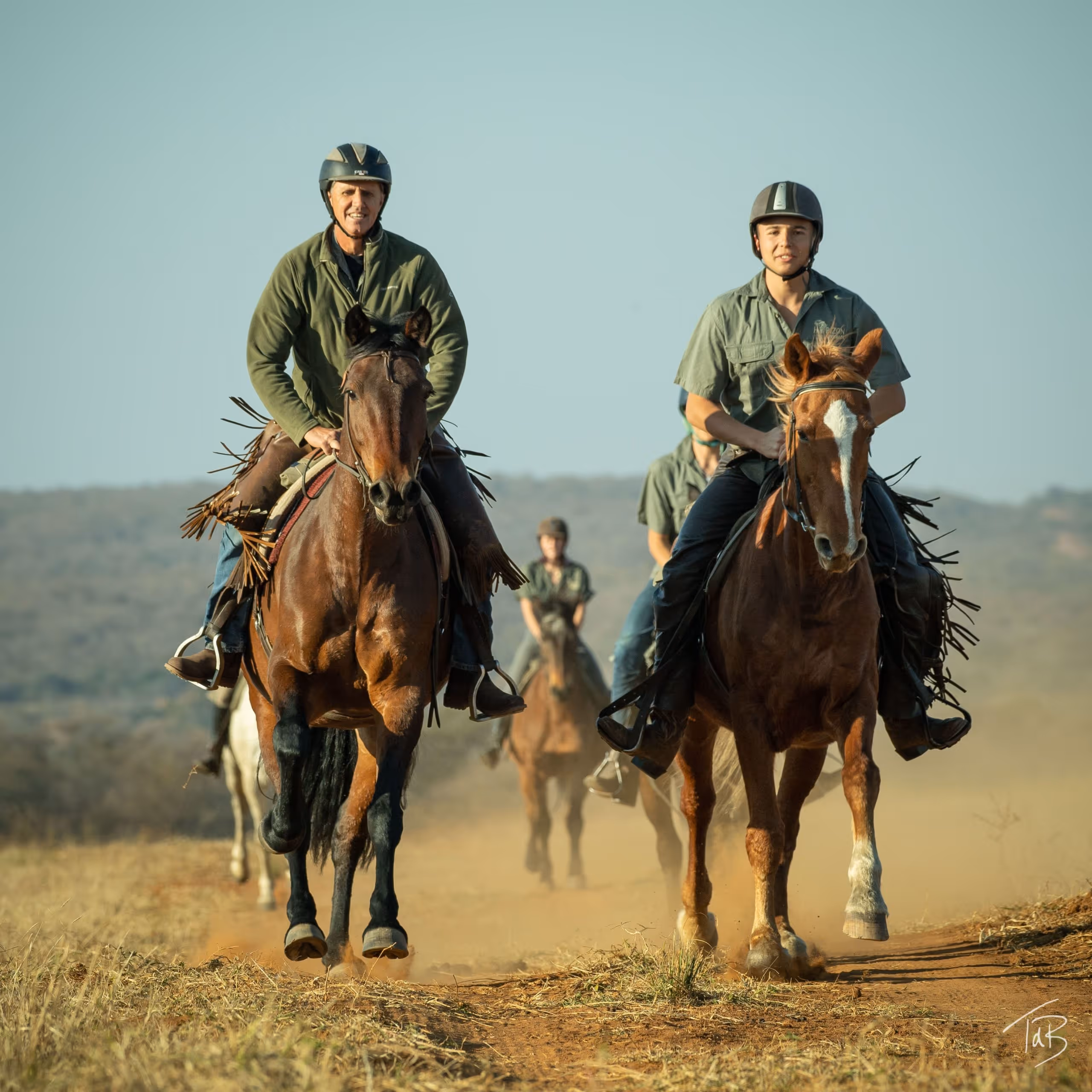 Un groupe de cavaliers traverse la savane africaine lors d’un safari équestre.