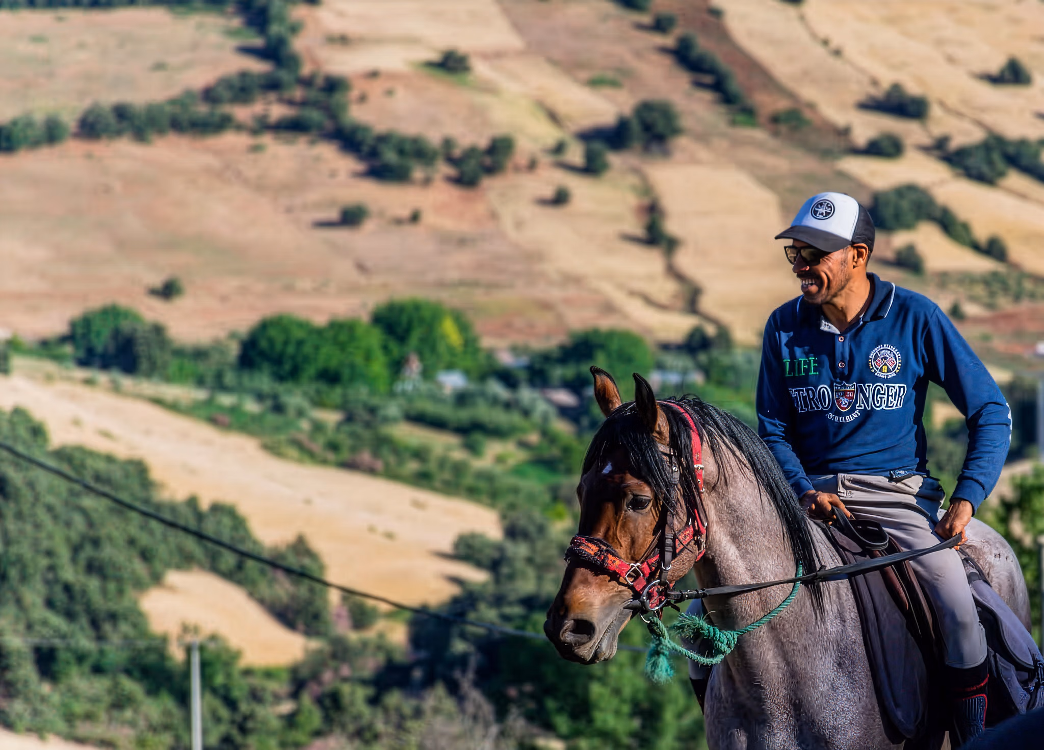 Un guide marocain souriant lors d’une randonnée à cheval dans le désert d’Agafay.
