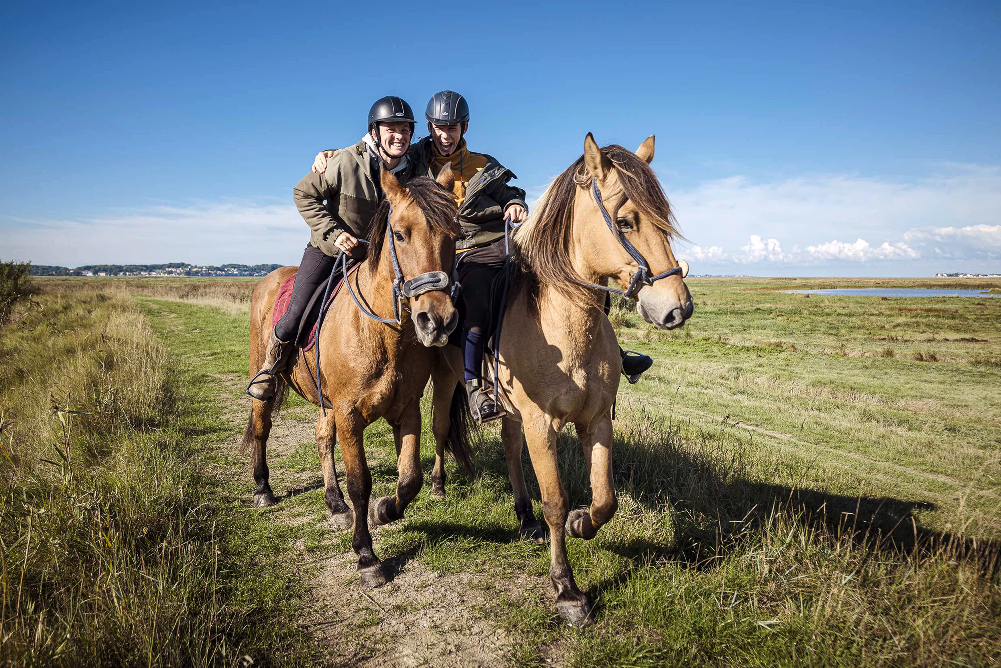 Deux amis se prenant dans les bras à cheval lors d’une randonnée ensemble.