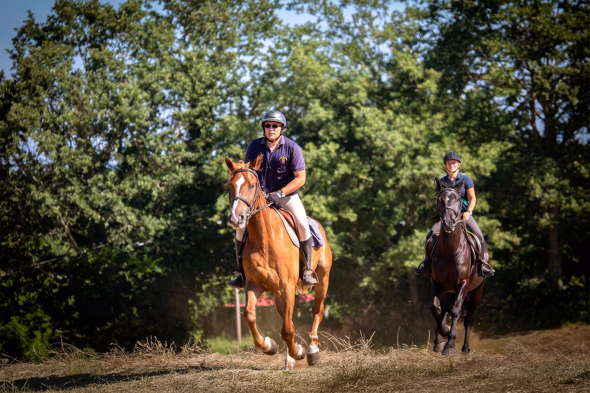 Un couple de cavaliers galope en direction de l’objectif en soulevant la poussière lors d’un voyage à cheval sur la Route des Brigands.