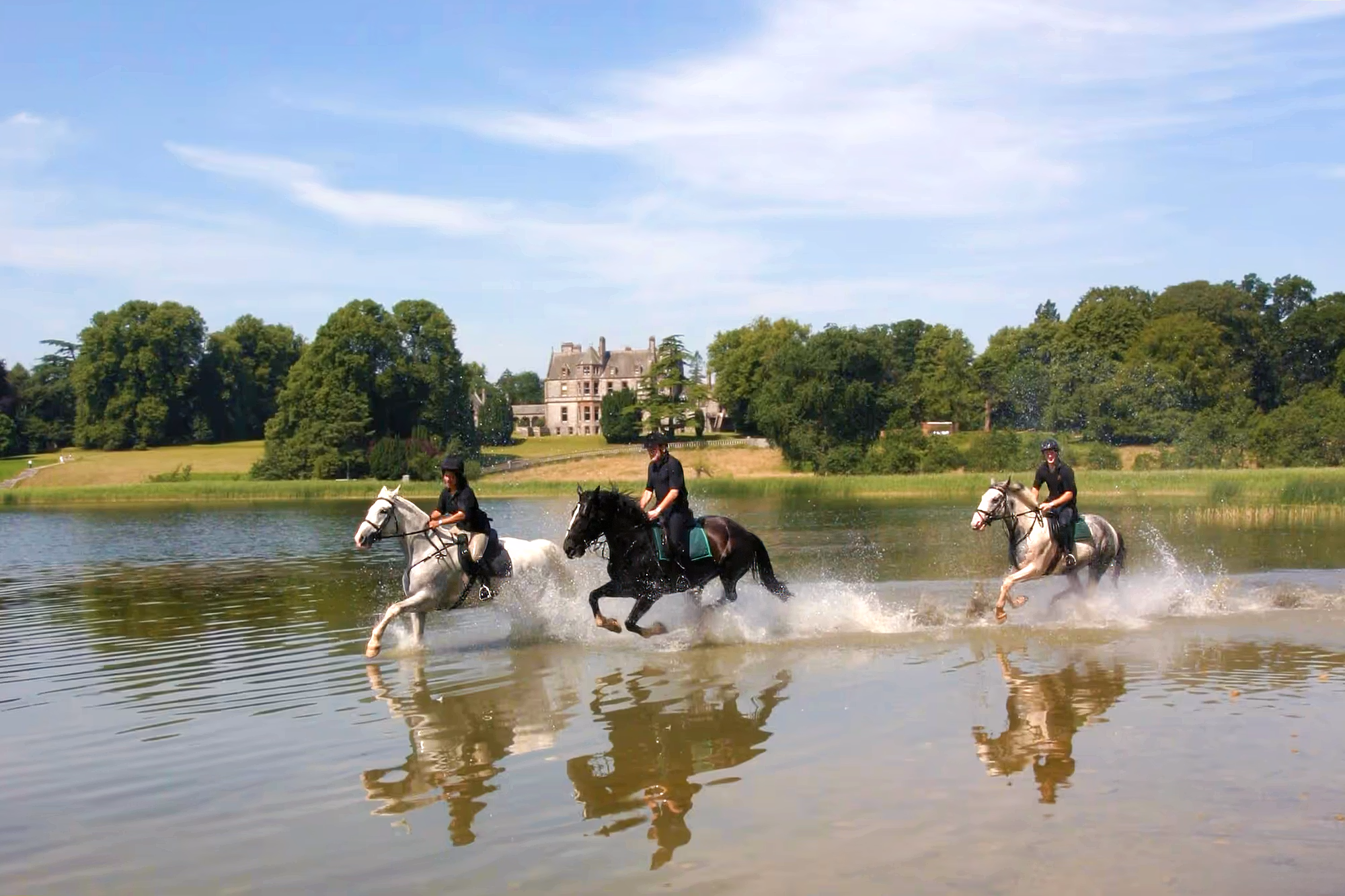 Un groupe de cavaliers traversant un lac lors d’un séjour équestre à Castle Leslie en Irlande.