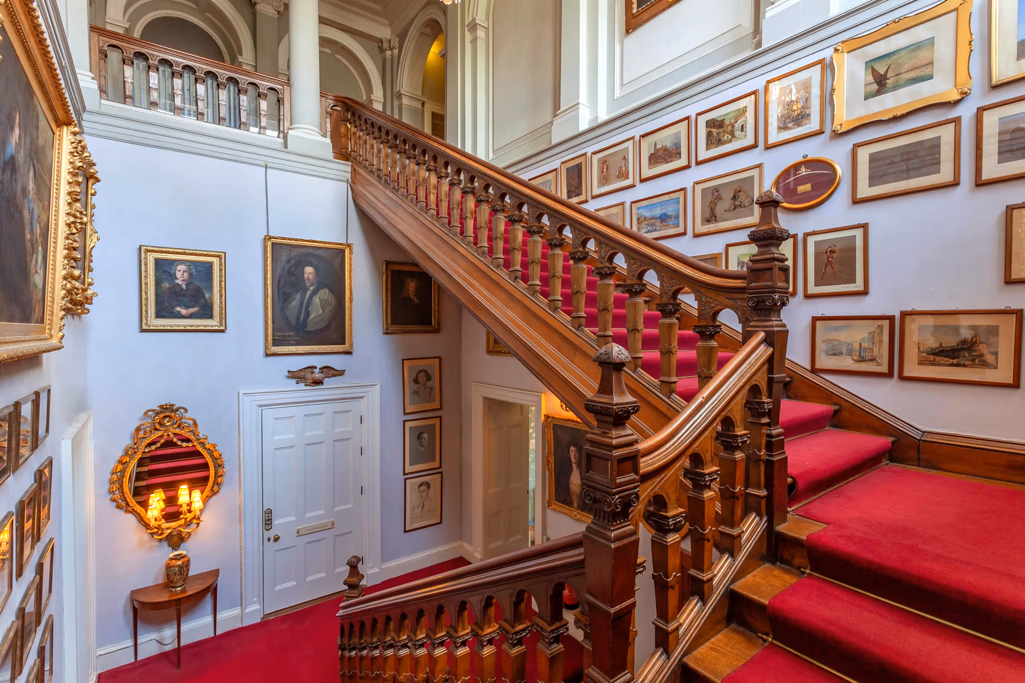 Un grand escalier intérieur en bois avec un élégant tapis rouge à Castle Leslie.