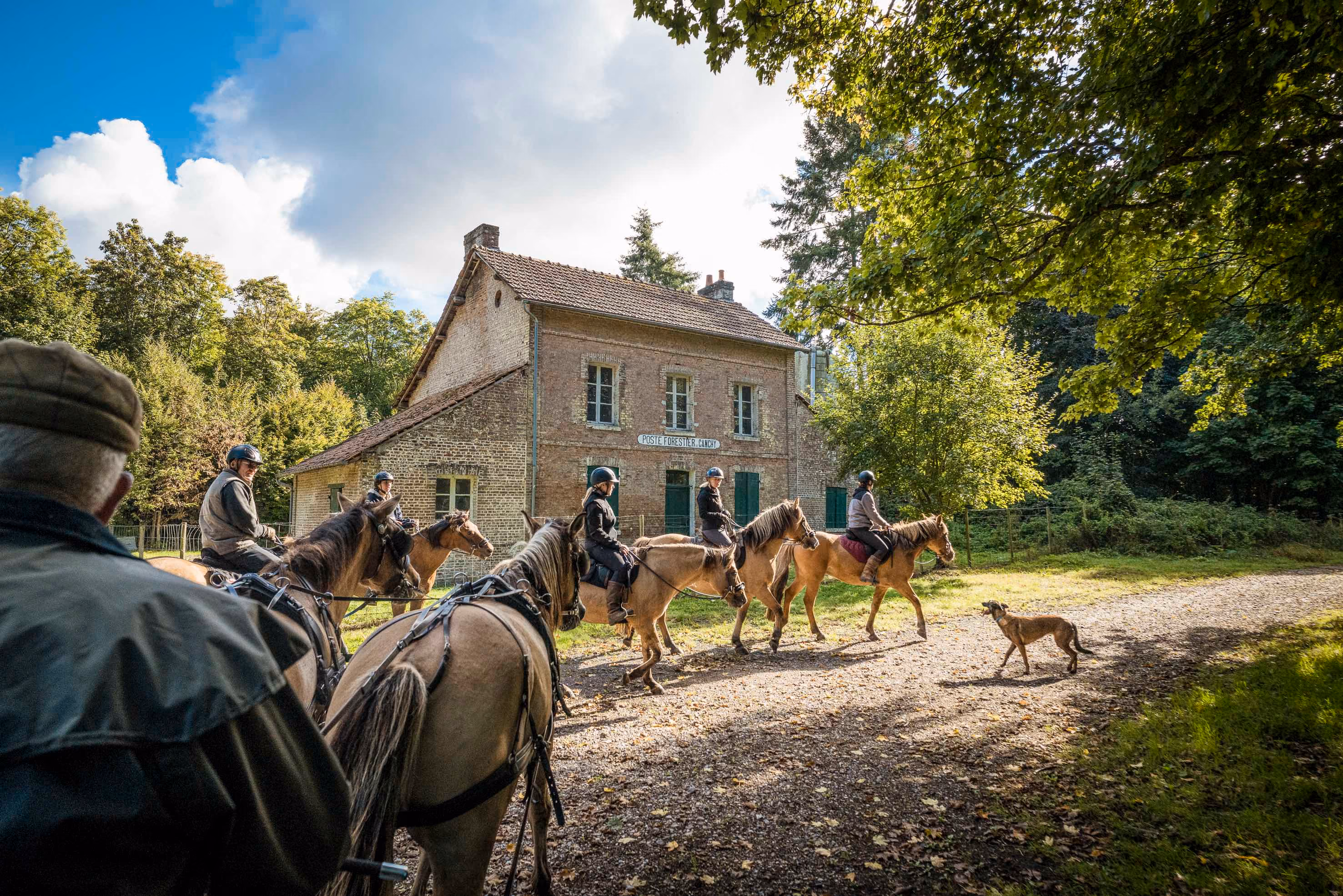 Un groupe de cavaliers passant devant un vieux poste forestier dans une foret du nord de la France.