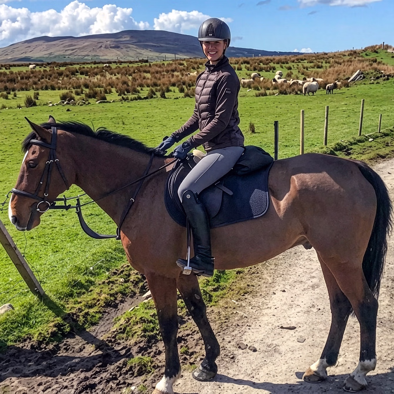 Une cavalière portant un casque suit un chemin à travers les champs verdoyants d’Irlande.