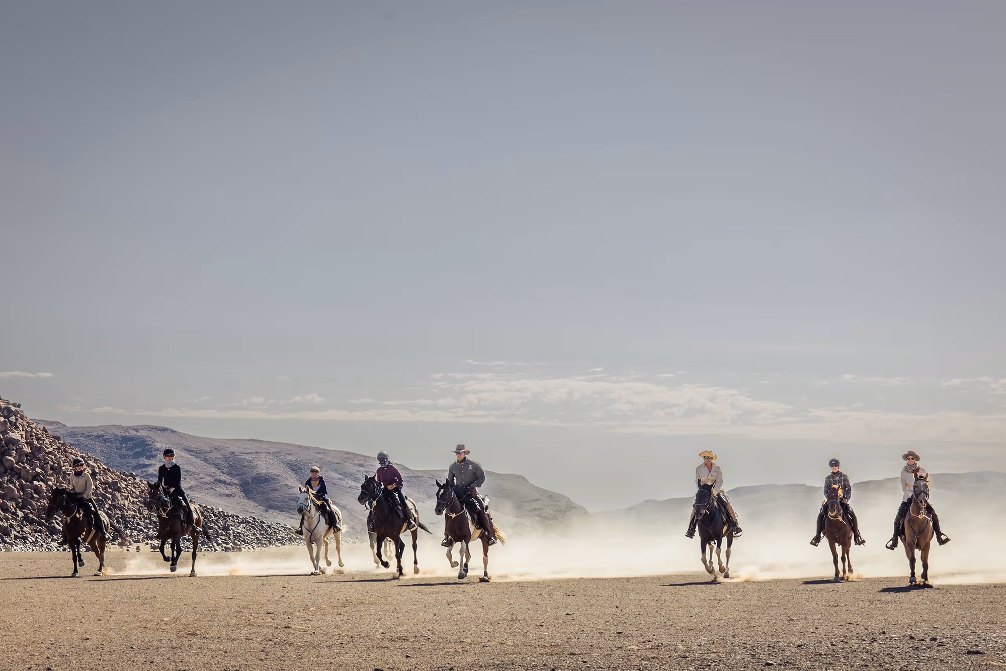 Un groupe de cavaliers galope vers l’objectif en soulevant un nuage de sable jaune.