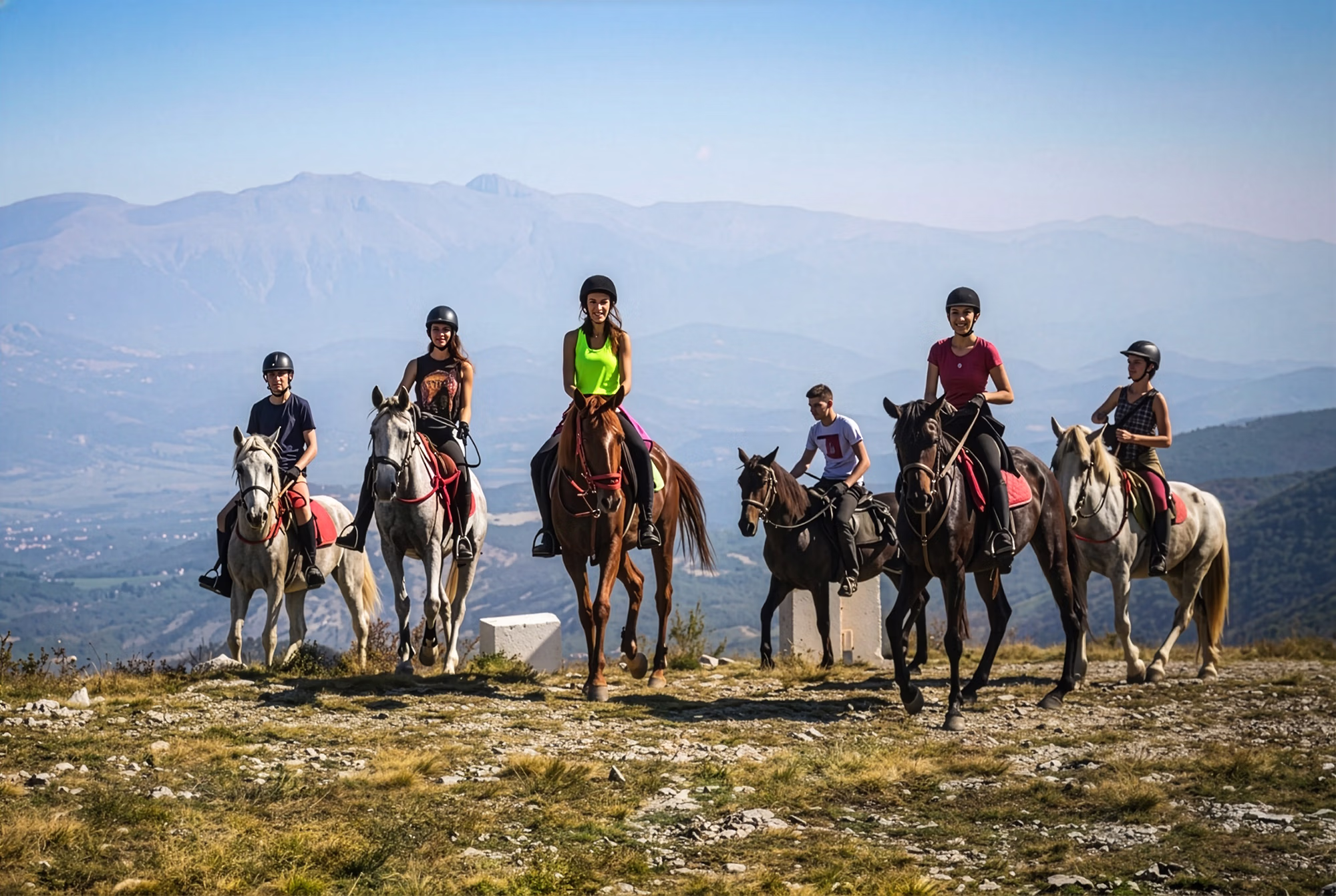 Un groupe de jeunes cavaliers franchit le sommet d’une colline, avec de magnifiques panoramas montagneux en toile de fond, lors de la randonnée équestre dans les montagnes dalmates en Croatie.