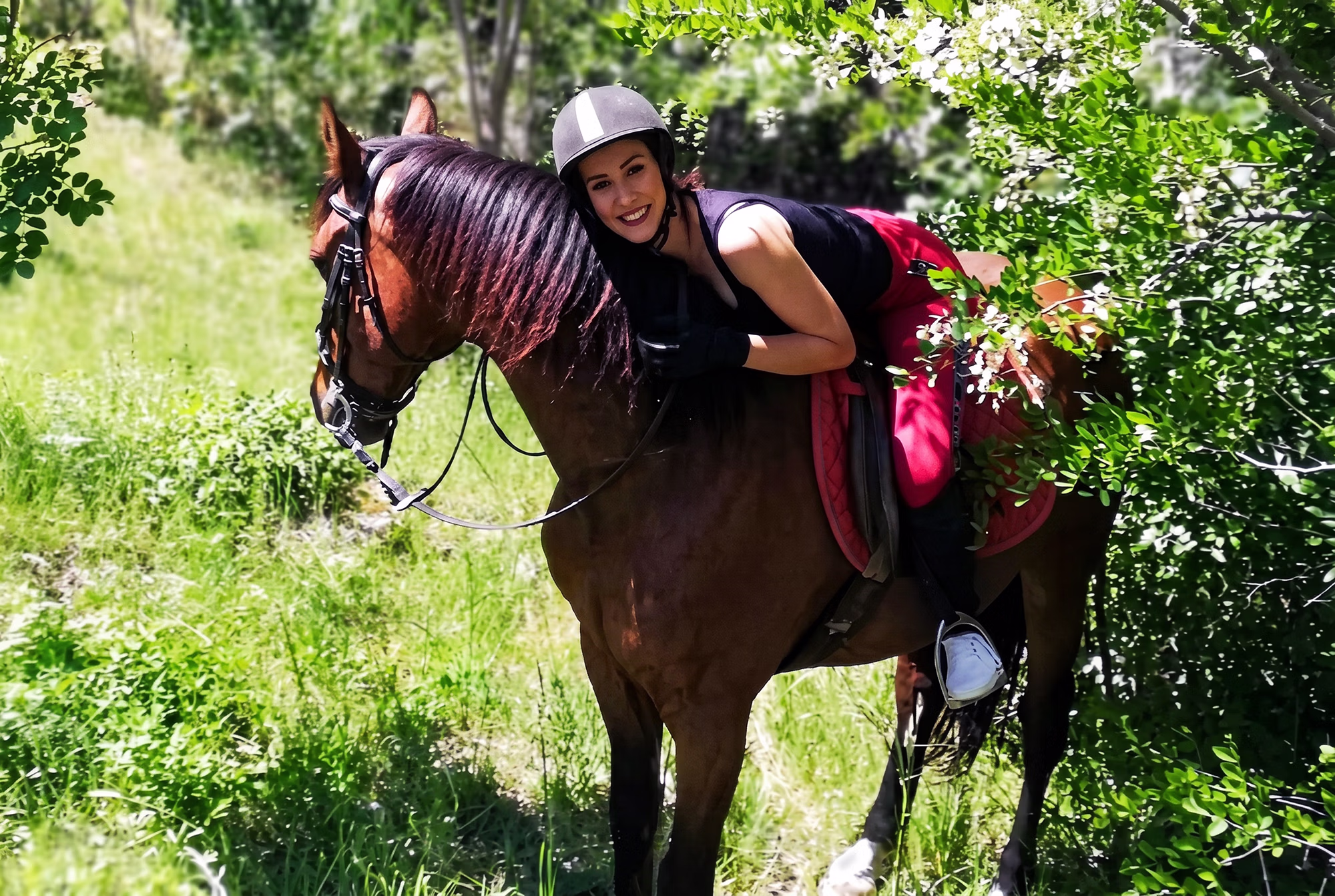 Une cavalière se penche en avant pour enlacer l’encolure de son cheval.
