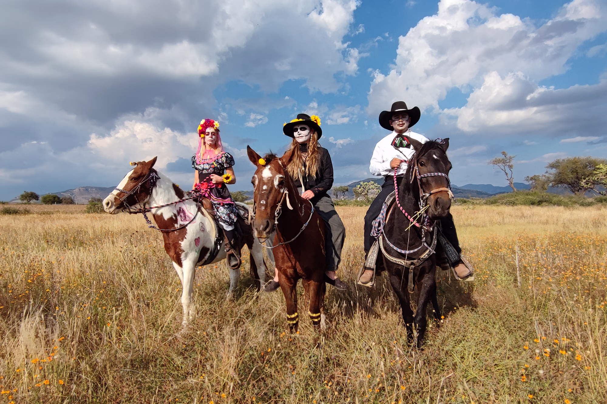 Trois cavaliers et leurs chevaux décorés aux couleurs du Día de los Muertos.